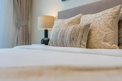 a bedroom with a bed with pillows and a lamp at Prime Location, Walking Distance to Circle Mall, Minutes Drive from Dubai Marina and Palm Jumeirah - Binghatti Aurora, JVC by Deluxe Holiday Homes in Dubai