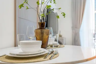 a table with plates and glasses and a vase at Prime Location, Walking Distance to Circle Mall, Minutes Drive from Dubai Marina and Palm Jumeirah - Binghatti Aurora, JVC by Deluxe Holiday Homes in Dubai