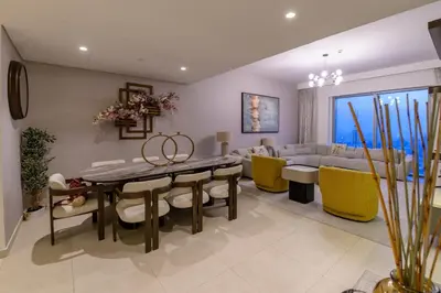 a dining room and living room with a table and yellow chairs at Stunning Apartment - Downtown View 2 - Tower 1 - Fountain and Burj Khalifa view 61st floor in Dubai