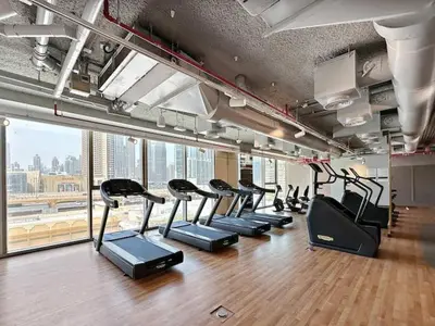 a gym with a row of treadmills in a room at Vogue Downtown Views II with Direct Access to Dubai Mall Via a Climate Controlled Bridge, One Bedroom Apartment with Balcony and City View in Dubai