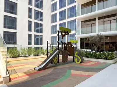 a playground in front of a tall building at SettlerHomes - Chic JVC Studio - Pool & Clubhouse in Dubai