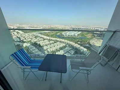 a balcony with two chairs and a table on a building at Cozy Studio Retreat in Damac Hills in Dubai