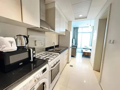 a kitchen with a stove top oven and a microwave at Cozy Studio Retreat in Damac Hills in Dubai