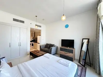 a white bedroom with a bed and a couch at Cozy Studio Retreat in Damac Hills in Dubai