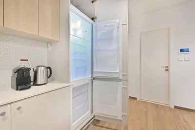 a kitchen with white cabinets and a refrigerator at Belgravia Heights 1 BHK in JVC in Dubai