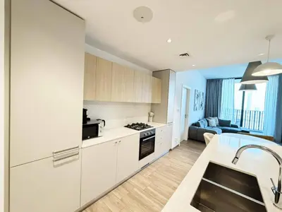 a kitchen with white cabinets and a living room at Belgravia Heights II 1 BHK in JVC Luxury Living in Dubai