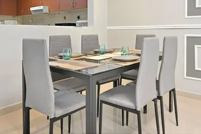 a dining room table with gray chairs and a table at Lake Point Tower 1 BHK by Petals Holiday Homes in Dubai