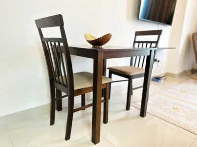 a wooden table with two chairs and a bowl on it at Comfortable Studio Retreat in Dubai Sports City in Dubai