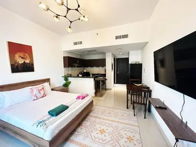 a bedroom with a large bed and a kitchen at Comfortable Studio Retreat in Dubai Sports City in Dubai