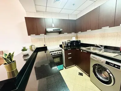 a kitchen with a washer and a sink and a dishwasher at Comfortable Studio Retreat in Dubai Sports City in Dubai
