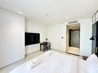 a white bedroom with a large bed and a flat screen tv at Elegant 1BR in Business Bay in Dubai