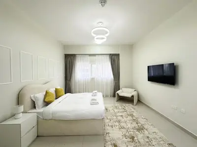 a bedroom with a large bed and a tv at Profile Residency Studio near Dubai Stadium by Petals Holiday Homes in Dubai
