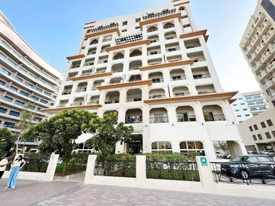 a large white building with a woman standing in front of it at Cordoba Palace Studio In Silicon Oasis by Petals Holiday Homes in Dubai