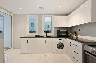 a kitchen with white cabinets and a washing machine at 5 BR Villa Near Business Bay By Petals Holiday Homes in Dubai