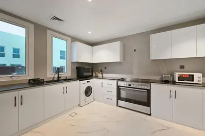 a large white kitchen with white cabinets and appliances at 5 BR Villa Near Business Bay By Petals Holiday Homes in Dubai