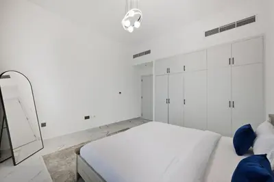 a white bedroom with a bed and a mirror at 5 BR Villa Near Business Bay By Petals Holiday Homes in Dubai