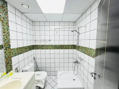 a white tiled bathroom with a shower and a sink at Indigo Tower 1 BR in JLT by Petals Holiday Homes in Dubai