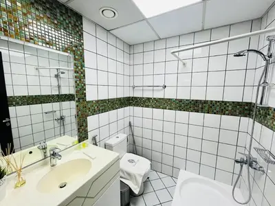a white tiled bathroom with a sink and a toilet at Indigo Tower 1 BR in JLT by Petals Holiday Homes in Dubai