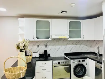 a kitchen with white cabinets and a washer and dryer at Indigo Tower 1 BR in JLT by Petals Holiday Homes in Dubai