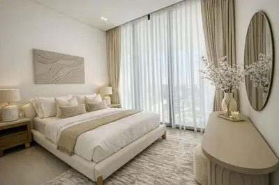 a white bedroom with a bed and a vase of flowers at Luxury 1BR in JVC Private Balcony Pool & Parking in Dubai