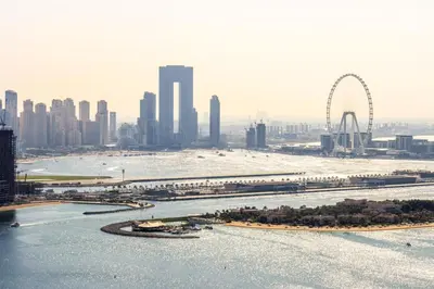 a view of a city with a river and a ferris wheel at Luxury 1BR on Palm Jumeirah with Pool Access and Beach in Dubai