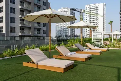 a row of lounge chairs and an umbrella on a lawn at Urban Oasis 1BR W Private Plunge Pool in Dubai