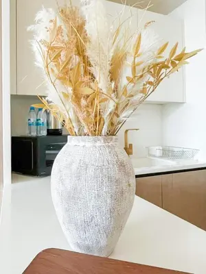a white vase sitting on a counter in a kitchen at Warm Modern 1BR Haven with Balcony & Free Parking in Dubai