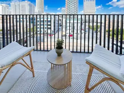 a balcony with two chairs and a table and a view of a city at Warm Modern 1BR Haven with Balcony & Free Parking in Dubai