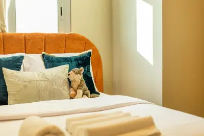 a teddy bear sitting on a bed with pillows at Stylish 2BHK Central Marina Rooftop Pool DEC T1 601 in Dubai