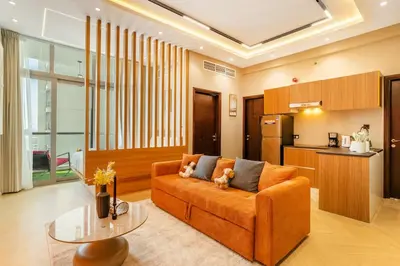a living room with an orange couch and a kitchen at Luxury 2BHK w Floating Bed in Dubai Marina DEC 1604 in Dubai
