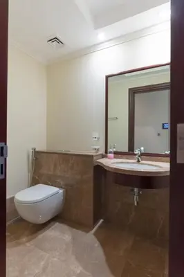 a bathroom with a toilet and a sink and a mirror at 2BHK in Palm Jumeirah Sea View Grandeur Residence 301 in Dubai