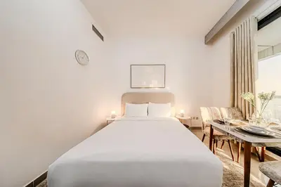 a white bedroom with a bed and a table at New Bright Studio in Escan Tower, For 2, Dubai Marina in Dubai