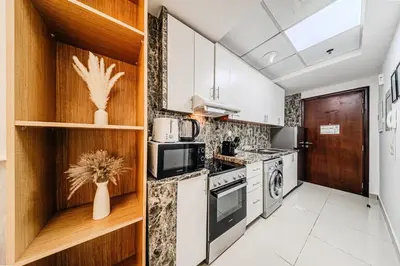 a kitchen with white cabinets and a stove at New Bright Studio in Escan Tower, For 2, Dubai Marina in Dubai