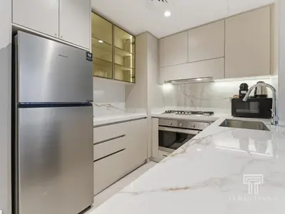 a kitchen with white cabinets and a stainless steel refrigerator at Brand New 2 Bed Contemporary Apt-Gym Pool Access in Dubai