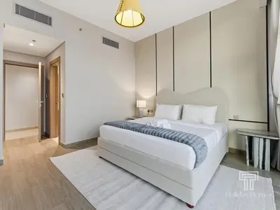 a bedroom with a large white bed and a table at Brand New 2 Bed Contemporary Apt-Gym Pool Access in Dubai