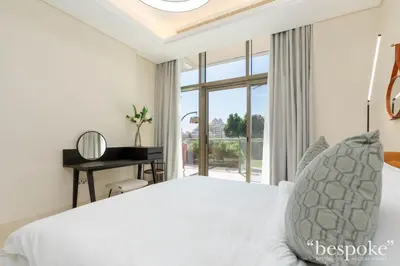 a bedroom with a bed and a desk and a window at Bespoke Holiday Homes - Elegant 2BR with Terrace in The 8 Palm Jumeirah in Dubai