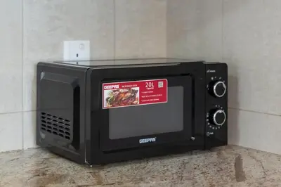 a black microwave with a sign on top of it at Greens Haven City & Golf View Balcony in Dubai