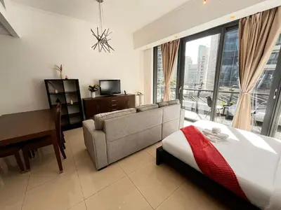a bedroom with a bed and a couch and a television at Elegant Studio, Marina access, Queen & Sofabed in Dubai