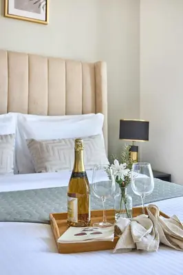 a tray with a bottle of wine and glasses on a bed at Frank Porter - Peninsula One in Dubai