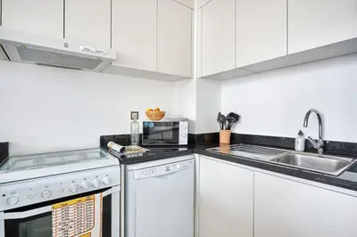 a kitchen with white cabinets and a sink and a microwave at Frank Porter - Damac Ghalia in Dubai