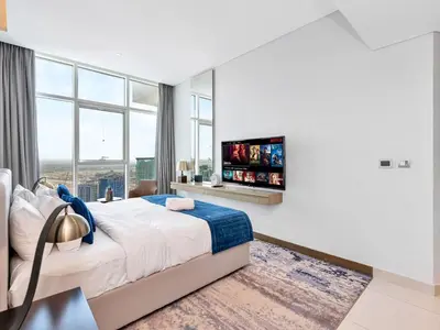 a bedroom with a large bed and a flat screen tv at Premium Studio Burj Khalifa & Canal View in Dubai