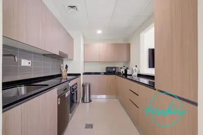 a large kitchen with wooden cabinets and stainless steel appliances at Ultra Luxury Villa 5BR With Maid Room in Dubai