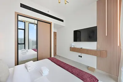 a bedroom with a white bed and a tv at Golden Stays - Private Pool Modern 2BR Oasis in JVC in Dubai