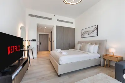 a bedroom with a white bed and a television at Arjan's Chic Studio with Cinema and Game Room in Dubai
