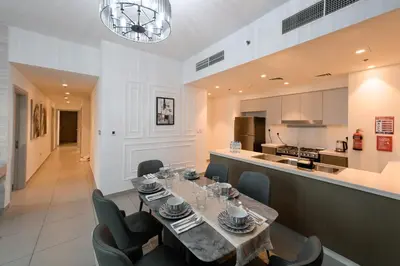 a dining room with a table and chairs and a kitchen at Forte 3BR Luxury PS5 Gaming Room Sleeps 9 in Dubai