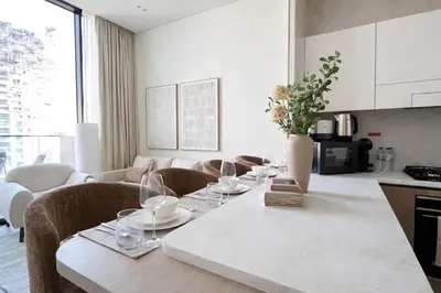 a kitchen and living room with a table with wine glasses at Stylish Stay with Plunge Pool & Scenic Pool View in Dubai