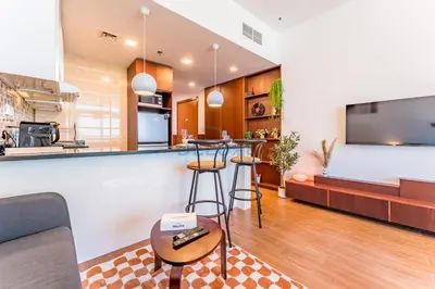 a kitchen and living room with a bar and a tv at Skyline Studio Overlooking the Community, Only a Few Steps from the Park, Al Jawhara Tower, Jumeirah Village Triangle by Deluxe Holiday Homes in Dubai