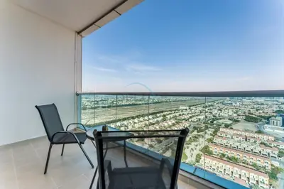 a balcony with a chair and a view of a city at Skyline Studio Overlooking the Community, Only a Few Steps from the Park, Al Jawhara Tower, Jumeirah Village Triangle by Deluxe Holiday Homes in Dubai