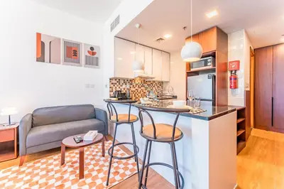a kitchen and living room with a bar and a couch at Skyline Studio Overlooking the Community, Only a Few Steps from the Park, Al Jawhara Tower, Jumeirah Village Triangle by Deluxe Holiday Homes in Dubai