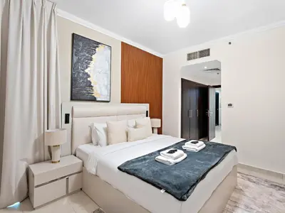 a white bedroom with a large bed with a blue blanket at Charming and Vibrant Living 1BDR In Marina Quay in Dubai